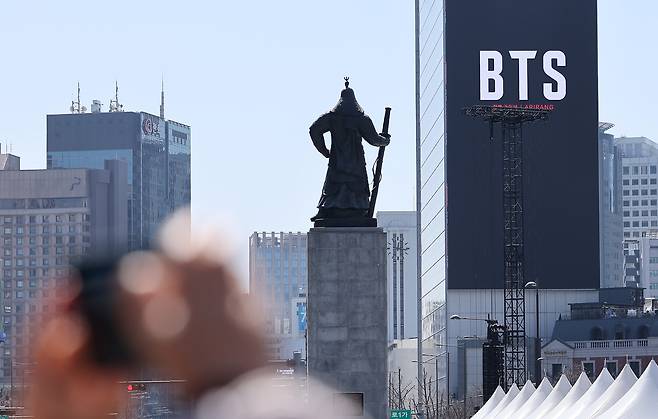 그룹 방탄소년단(BTS)의 서울 광화문광장 컴백 공연이 이틀 앞으로 다가온 19일 서울 종로구 광화문광장에서 시민들이 한 건물 외벽에 부착된 BTS 컴백 공연 광고물을 스마트폰으로 촬영하고 있다. /뉴스1