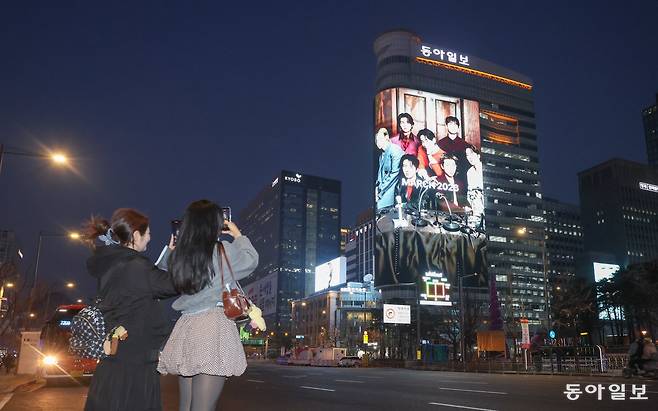 방탄소년단(BTS)의 컴백 공연 ‘BTS 컴백 라이브: ARIRANG(아리랑)’을 하루 앞둔 20일 국내 최대 규모의 미디어 사이니지인 ‘룩스(LUUX)’에 공연 관련 영상이 송출되고 있다. 카자흐스탄에서 온 ‘아미’들이 영상을 찍고 있다. 김재명 기자 base@donga.com