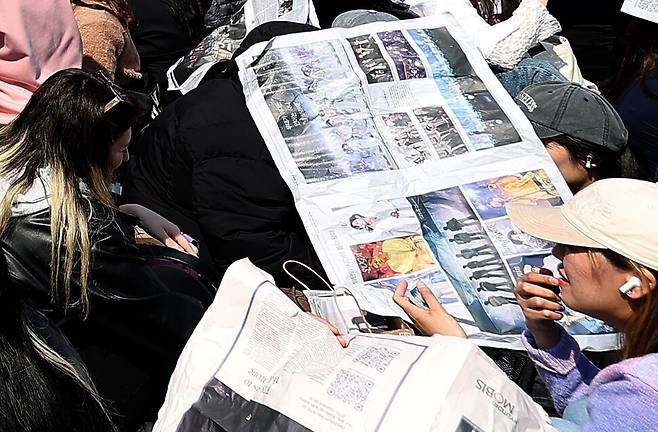 그룹 방탄소년단(BTS) 광화문 컴백 콘서트를 앞둔 21일 오후 서울 광화문광장 공연장 밖에서 \'아미\'(BTS 팬덤)들이 공연을 기다리며 한겨레 BTS 특별판을 보고 있다. 연합뉴스