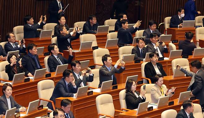 더불어민주당은 20일 국회에서 ‘공소청 법안’을 의결했다. 이날 여당 의원들이 법안이 통과된 뒤 휴대폰으로 전광판을 촬영하고 있다. [연합뉴스]