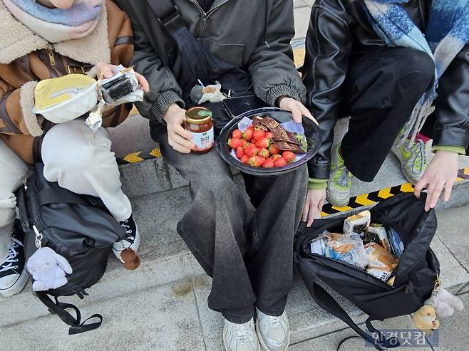 21일 오전 10시경 독일에서 온 20대 여성 루시씨가 광화문 광장 계단 위에 앉아 즉석밥에 조미김을 싸서 먹고 있다. 그와 함께 온 여동생 에밀리, 남동생 A씨가 딸기, 식빵, 딸기쨈 등 아침, 점심, 저녁을 해결하기 위해 싸온 음식을 보여주고 있다. /사진=박수빈 기자