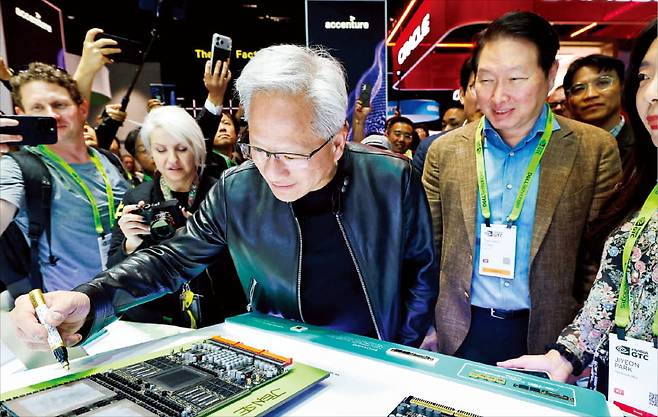 젠슨 황 엔비디아 CEO가 최태원 SK그룹 회장이 지켜보는 가운데 SK하이닉스의 HBM4가 탑재된 베라 루빈 AI 가속기 시제품에 서명하고 있다.