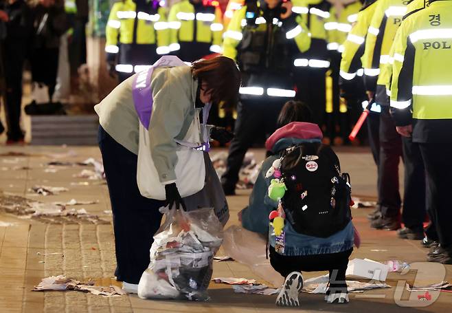 21일 오후 서울 종로구 광화문광장에서 열린 'BTS 컴백 라이브: 아리랑'이 끝난 후 한 아미 자원봉사단원이 쓰레기를 치우고 있다. 2026.3.21 ⓒ 뉴스1 김진환 기자