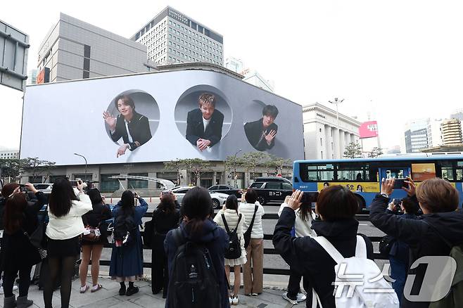 방탄소년단(BTS) 컴백 공연 다음 날인 22일 오전 서울 중구 신세계백화점 인근에서 방탄소년단의 팬클럽 ARMY가 송출되는 BTS의 모습을 사진 찍고 있다. 2026.3.22 ⓒ 뉴스1 김민지 기자