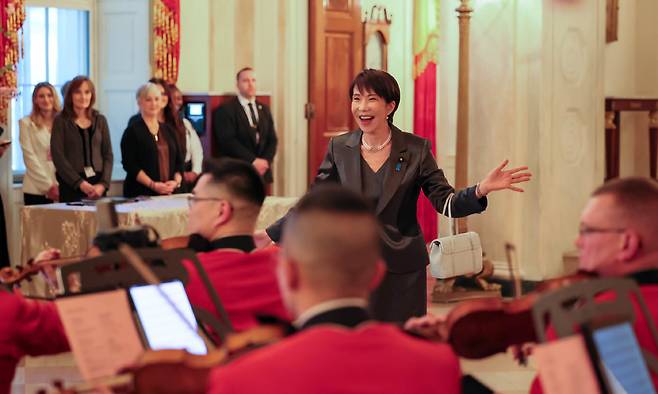 지난 19일(현지시간) 방미 중인 다카이치 사나에 일본 총리가 백악관 만찬장에 들어서기 전 미군&nbsp;군악대의&nbsp;‘러스트 네일’ 연주를 들으며 기뻐하고 있다. 다카이치 총리 SNS 캡처