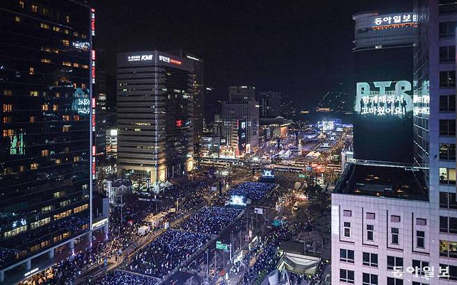 21일 오후 서울 세종대로 고층 건물에서 내려다본 광화문광장. ‘BTS 컴백 라이브: 아리랑’ 공연이 열리는 야외 객석이 수많은 응원봉 불빛으로 가득 차 있다. 미디어 사이니지 ‘룩스’(오른쪽)에선 BTS 관련 영상이 나오고 있다. 박형기 기자 oneshot@donga.com