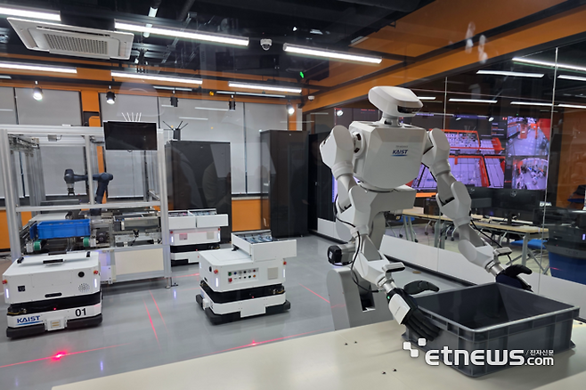 23일 대전 유성 KAIST 피지컬 AI 테스트베드 '카이로스'에서 로봇이 트레이를 운반하기 위해 잡고 있다. 테스트베드 외부 오른쪽 뒤편 화면은 통합 관제 시스템 모니터. ⓒ박종진기자