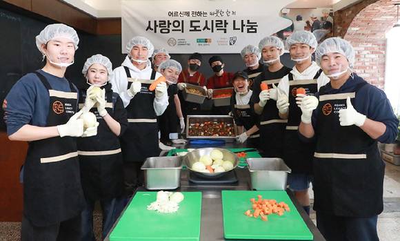 지난 22일 서울 용산구에 위치한 공유주방 '레거시 키친'에서 현대그린푸드 조리사와 서울외국인학교 봉사동아리 그로우앤기브 소속 학생들, 코리아레거시 직원들이 저소득층 노인 가구와 노인무료급식소 등에 전달할 갈비찜 도시락을 만들고 있는 모습. [사진=현대그린푸드]