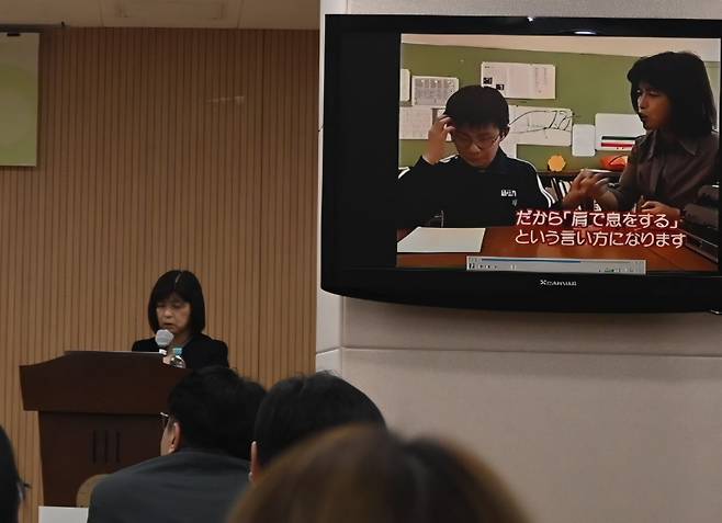 호시 유코 요코하마 훈맹학원장이 일본 현지의 시청각장애 아동 교육 사례 영상을 소개하며 강연하고 있다. 모니터 속 영상은 아이가 운동 후 가빠진 호흡을 통해 ‘어깨로 숨을 쉰다’는 관용구를 몸으로 직접 배우는 장면이다.