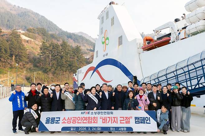24일 오전 울릉 사동항에서 ‘울릉군 소상공인연합회’ 회원들이 공식 출범식에 앞서 대형 카페리 선(뉴씨다오펄호)을 배경으로 현수막을 들고 입도 관광객 대상 ‘바가지요금 근절 및 친절 캠페인’을 전개한 뒤 기념 촬영을 하고 있다. /황진영 기자