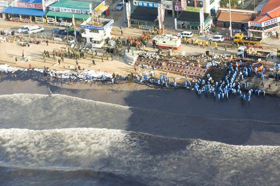 2007년 12월 8일 유조선과 크레인선 충돌사고 이튿날 충남 만리포 해수욕장으로 밀려든 기름을 삼성자원봉사단원(파란 옷)들과 주민들이 퍼내고 있다. 중앙포토