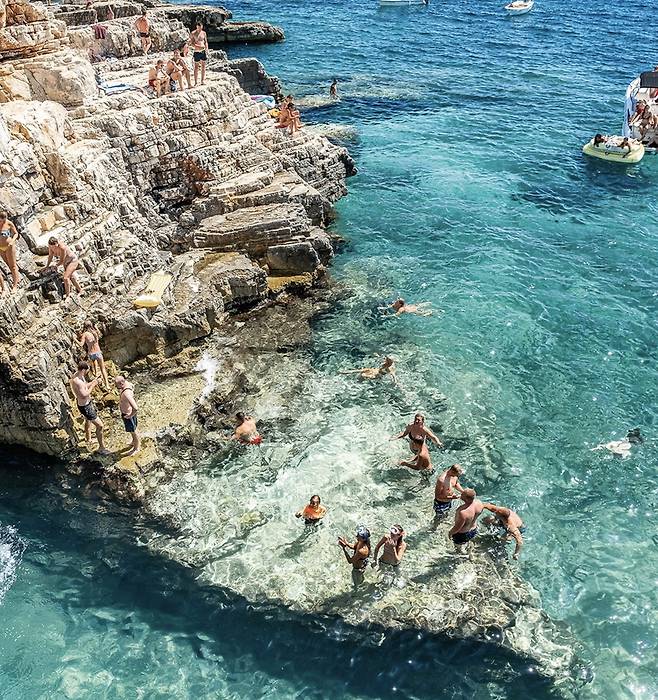 에메랄드빛으로 빛나는 투명한 바다와 층층이 쌓인 해안 절벽이 조화를 이루는 천연 수영장에서 여유롭게 수영과 다이빙을 즐기는 여행객들. 사진제공|CNTB