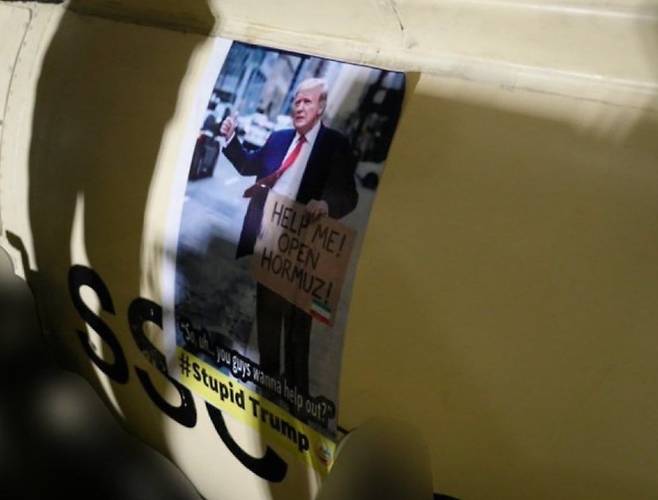 이슬람혁명수비대가 미사일에 붙인 합성 사진에 트럼프 대통령이 "호르무즈 열게 좀 도와줘"라는 문구가 적힌 손팻말을 든 모습이 담겼다. /텔레그램