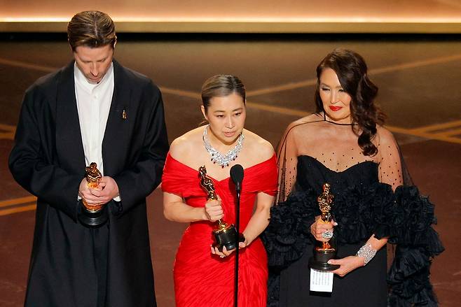 지난 15일 아카데미 시상식에서 ‘케이팝 데몬 헌터스’ 감독 매기 강이 수상 소감을 밝히고 있다. 한국계 캐나다인인 그는 K컬처의 글로벌 협업을 상징하는 인물이 됐다. ‘케데헌’은 더이상 ‘국위선양’의 논리로 K컬처를 설명할 수 없음을 보여준다. [로이터=연합뉴스]