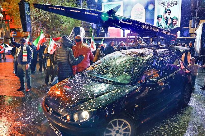 26일(현지시간) 이란 테헤란에서 시민들이 이란 미사일 모형을 탑재한 차량 옆에서 반미·반이스라엘 집회를 열고 있다. [로이터 = 연합뉴스]