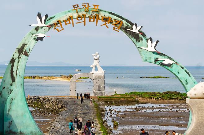 무창포 '신비의 바닷길'은 밀물이 시작되면 금세 물에 잠긴다. 지난 20일에 새롭게 들어선 상징 조형물 '사랑의 문' 아래에서 물때를 놓친 '지각 여행객'들이 물에 잠긴 바닷길을 보며 아쉬운 마음을 달래고 있다. / 이건송 영상미디어 기자