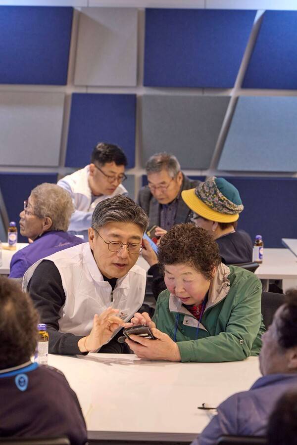 정재헌 SKT CEO가 경기도 포천시 관인노인대학에서 어르신 고객의 스마트폰을 살펴보고 대화를 나누는 모습. [출처= SK텔레콤]