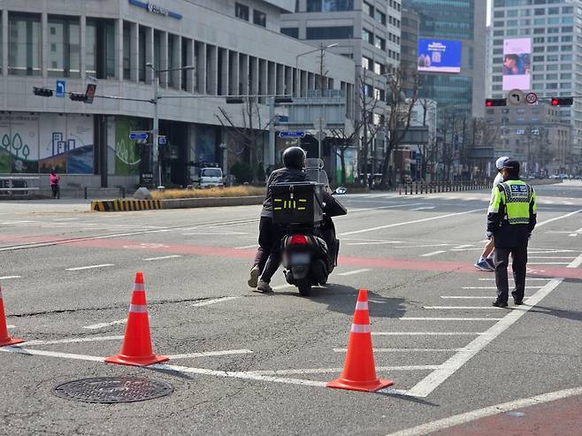 한 배달원이 교통통제 구역에서 오토바이에서 내려 끌고 이동하고 있다. /사진=이정우 기자