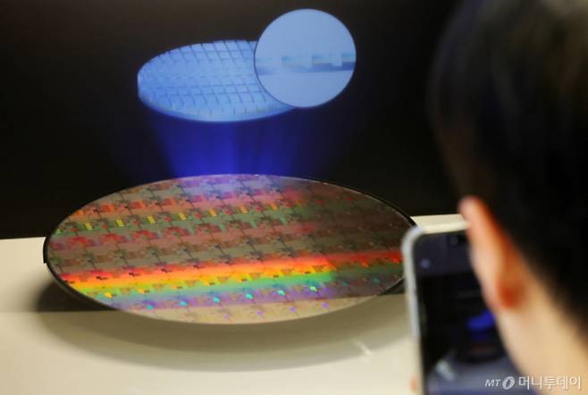 [서울=뉴시스] 조성우 기자 = 11일 오후 서울 강남구 코엑스에서 열린 세미콘 코리아 2026를 찾은 한 관람객이 반도체 웨이퍼 사진을 찍고 있다. 2026.02.11. xconfind@newsis.com /사진=조성우