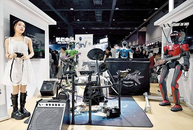 中 휴머노이드 로봇 밴드   28일 중국 베이징에서 열린 ‘베이징 공상과학(SF) 카니발’ 행사장에서 한 여성이 링바오 카스봇(Lingbao Casbot)사의 로봇들과 함께 포즈를 취하고 있다. /연합뉴스 AFP
