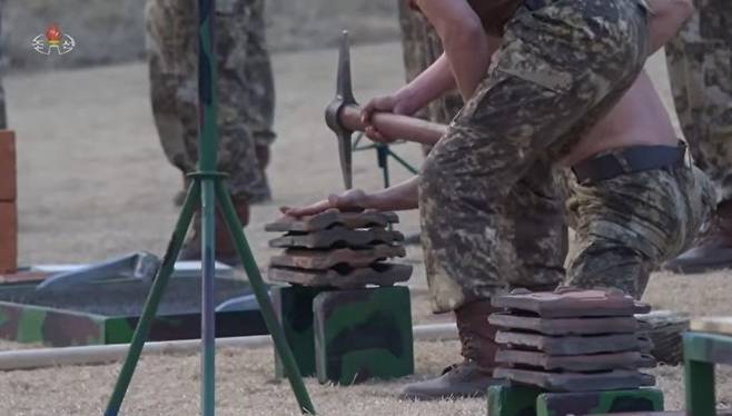 조선중앙TV는 29일 전투원들이 김정은 노동당 총비서 앞에서 진행한 시범 장면을 보도했다. 기왓장 위에 있는 손을 낫으로 내려쳐 격차하는 모습. 사진=조선중앙TV 캡처