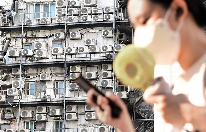 한 시민이 서울 중구 남대문 인근에 있는 건물 외벽에 줄지어 걸린 에어컨 실외기 앞을 지나가고 있다. 이상섭 기자