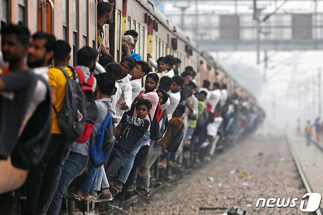 인도 우타르프라데시주 가지아바드에 있는 로니의 기차역에서 승객들이 열차에 매달려 있는 모습. ⓒ AFP=뉴스1