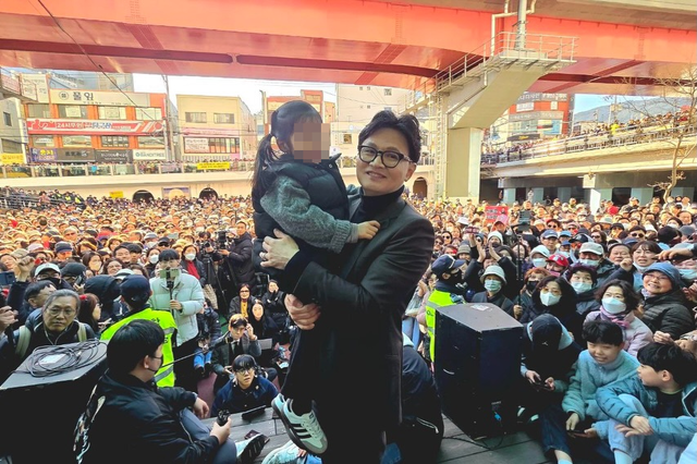 한동훈 전 국민의힘 당대표가 지난 3월 7일 부산 북구 구포시장 방문에 이어 연제구 온천천 일대에서 ‘해피워크’에 동참한 시민들을 만나며 한 아이를 안아들고 있다.[한동훈 전 법무부 장관 페이스북 사진]