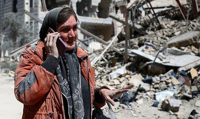 30일(현지시각) 이란 테헤란에사 한 여성이 공습으로 파괴된 주거 지역 한가운데서 전화 통화를 하고 있다. 로이터 연합뉴스