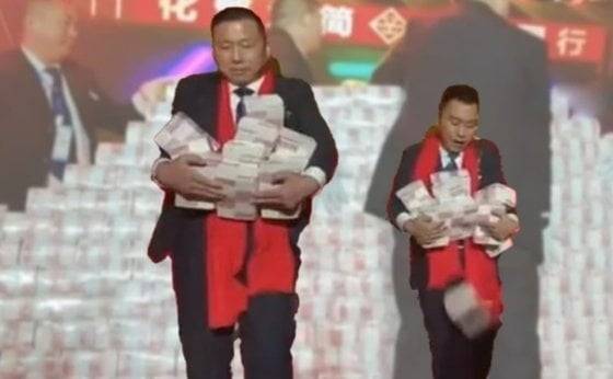 복지기업으로 소문난 중국 중장비기업 허난광산그룹이 2023년 개최한 연말 행사에서 직원들 2m 높이 ‘현금탑’에서 각자 돈을 꺼내 옮기고 있다. 웨이보 캡처