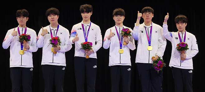 항저우 아시안게임 e스포츠 리그 오브 레전드(LoL)에서 금메달을 딴 한국 선수들이 시상대에 올라 포즈를 취하고 있다. 왼쪽부터 '제우스' 최우제, '카나비' 서진혁, '쵸비' 정지훈, '페이커' 이상혁, '룰러' 박재혁, '케리아' 류민석. 연합뉴스