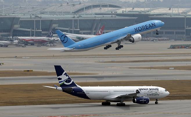 지난달 30일 인천국제공항 계류장에 대기하는 항공기 앞으로 대한항공 항공기가 이륙하고 있다. [뉴스1]