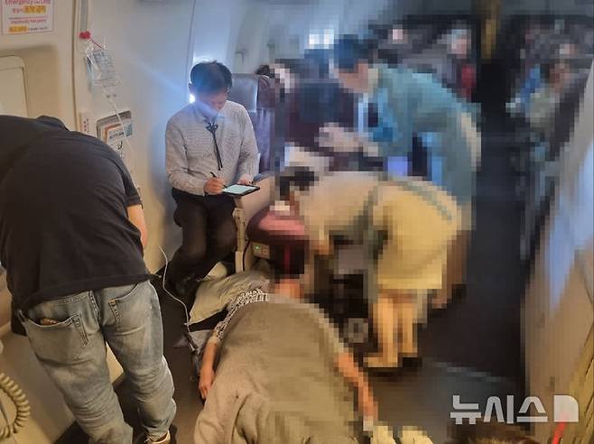 [서울=뉴시스] 김철민 서울성모병원 가정의학과 교수가 환자의 에어웨이(airway)를 확보하고 환자 소생시킨 후, 기장과 회항여부 등을 상의하며 응급상황이 발생한 비행기 안 현장을 조직적으로 지휘하고 있다. (사진= 독자 제공)