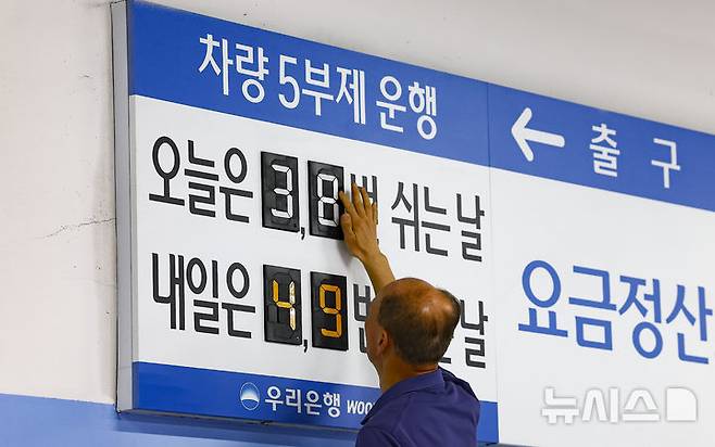 [서울=뉴시스] 김근수 기자 = 공공부문 승용차 5부제 의무화 첫날이자 금융업계도 차량 5부제 운행에 동참한 가운데 25일 오전 서울 중구 우리은행 본점 주차장에서 한 주차 안내원이 숫자를 조정하고 있다. 2026.03.25. ks@newsis.com