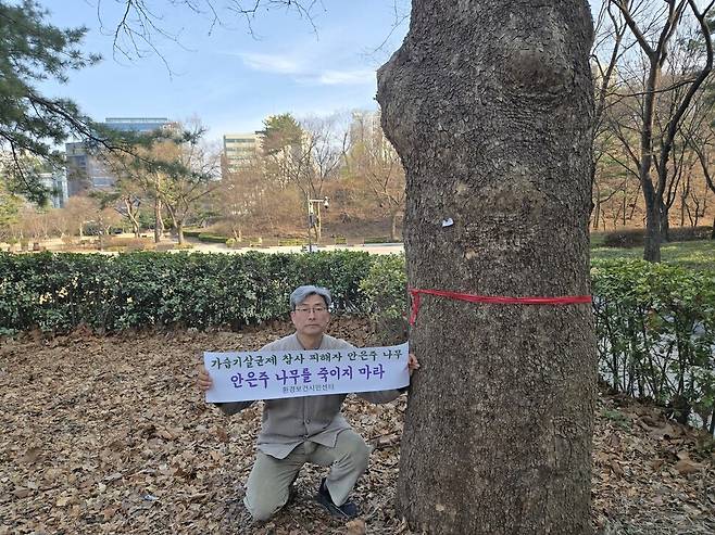 2026년 3월23일 서울 종로구 경희궁 서쪽 키가 약 60m인 플라타너스 옆에서 최예용 환경보건시민센터 소장이 ‘안은주 나무를 죽이지 마라’라고 적힌 펼침막을 들고 있다. 김양진 기자