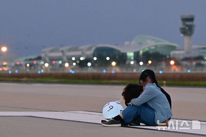 [무안=뉴시스] 이영주 기자 = 추석 당일인 6일 오후 전남 무안군 무안국제공항 활주로에서 12·29 무안공항 제주항공 여객기 참사 유가족협의회가 참사 희생자들의 넋을 위로하며 '기억의 활주로, 별이 된 당신께' 유등행사를 진행하고 있다. 행사 진행 도중 한 유족이 주저앉아 절규하고 있다. 2025.10.06. leeyj2578@newsis.com