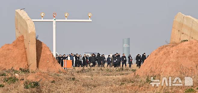 [무안=뉴시스] 이영주 기자 = 제주항공 여객기 참사 1주기인 29일 오후 전남 무안국제공항 활주로 콘크리트 둔덕(로컬라이저) 사이로 추모 행사를 위해 이동 중인 유가족들이 보이고 있다. 2025.12.29. leeyj2578@newsis.com