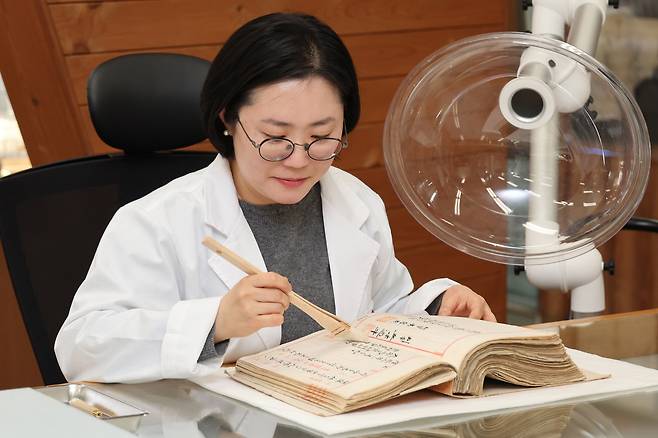 조은혜&nbsp;국가기록원 복원관리과 학예연구사가 지난 3월25일 경기 성남시 국가기록원 성남분원에서 1909년 대한제국 시절 작성된 판결문인 ‘형사재판 원본’&nbsp;기록물 표면의 오염 물질을 붓으로 없애는 건식 클리닝을 시연하고 있다. 사진 오른쪽 장비는 집진기 일종인 국소 배기 장치다. 성남=이제원 선임기자