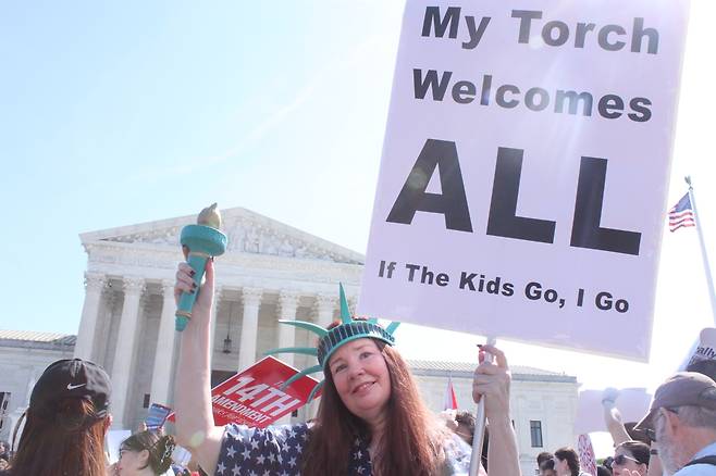 자유의 여신상 복장으로 나온 시위대  (워싱턴=연합뉴스) 백나리 특파원 = 1일(현지시간) 도널드 트럼프 미 대통령의 출생시민권 금지 행정명령이 적법한지를 두고 변론을 연 연방대법원 앞에서 자유의 여신상 복장을 한 시위 참가자가 피켓과 횃불을 들어 보이고 있다. 2026.4.2. nari@yna.co.kr