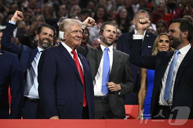 15일(현지시간) 미 위스콘신주 밀워키 파이서브포럼에서 개막한 공화당 전당대회에 대선 후보인 도널드 트럼프 전 대통령이 귀에 붕대를 한 채 모습을 드러내자 그의 두 아들과 이날 부통령 러닝메이트로 지명된 제임스 데이비드 (J.D.) 밴스 상원의원(오하이오)이 주먹을 불끈 쥔 손을 치켜들고 그를 맞이하고 있다.  2024.07.16 ⓒ AFP=뉴스1
