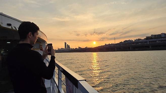 우즈베키스탄에서 온 외국인 관광객이 1일 오후 한강버스에서 석양을 촬영하고 있다. /윤희훈 기자