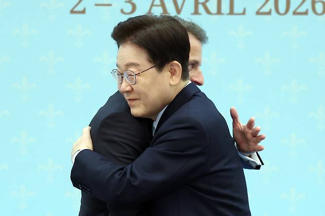 President Lee Jae Myung and French President Emmanuel Macron embrace after a joint press conference at Cheong Wa Dae in Seoul on Friday. (Yonhap)