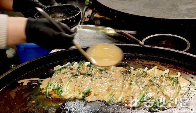차곡히 쌓인 쪽파와 해물 위에 맛국물을 붓고 펼쳤다 접으면서 두껍게 만들면 완성이다. 부산=김도웅 프리랜서 기자