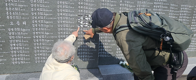 4·3희생자 유족이 각명비 앞에서 참배를 드린 뒤 가족 이름을 가리키며 얘기를 나누고 있다. 제주 강동삼 기자