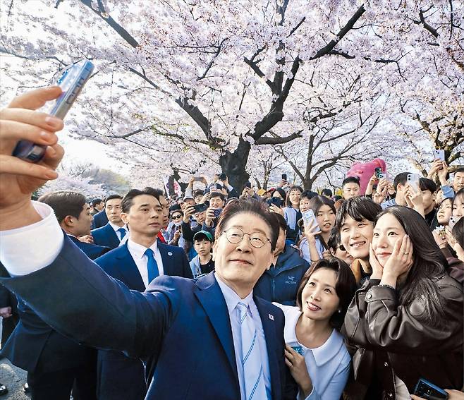 李대통령 부부, 여의도 벚꽃길서 시민들과 셀카  이재명 대통령과 김혜경 여사가 5일 ‘여의도 봄꽃축제’가 열린 서울 여의도 여의서로 벚꽃길을 찾아 시민들과 함께 사진을 찍고 있다. /청와대