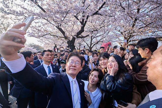 이재명 대통령과 김혜경 여사가 5일 봄꽃 축제가 열리고 있는 서울 여의도 윤중로에서 시민들과 벚꽃을 배경으로 기념 촬영을 하고 있다. [청와대]