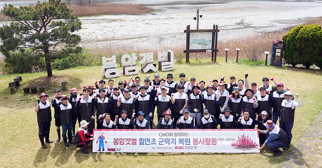 봉암갯벌 칠면초 군락지 복원 봉사활동에 참여한 경남은행 행원들이 기념촬영을 하고 있다. ⓒBNK경남은행 제공