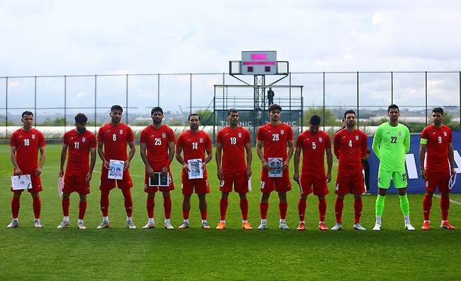 이란 축구대표팀 선수들이 지난달 31일 터키 안탈리아 마르단 스포츠 콤플렉스에서 열린 코스타리카와의 평가전에 앞서 전쟁으로 파괴된 건물과 희생된 어린이들의 사진을 들고 도열하고 있다. 로이터