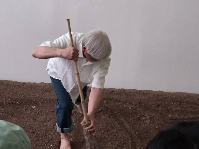 이배 작가  (원주=연합뉴스) 박의래 기자 = 이배 작가가 6일 강원도 원주 뮤지엄 산에 구현된 논에서 싸리 빗으로 붓질을 하고 있다. 2026.4.6. laecorp@yna.co.kr