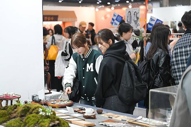 Two young visitors examine teaware items at a booth at the 2026 Seoul International Buddhism Expo. (Seoul International Buddhism Expo 2026)